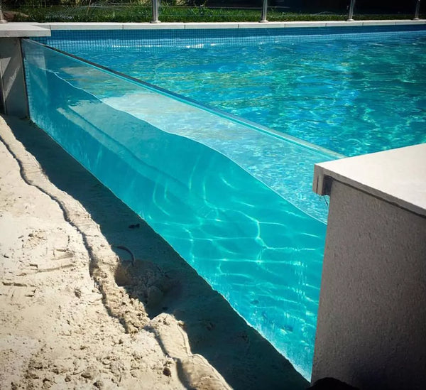 Long transparent acrylic swimming pool wall beside a stone terrace