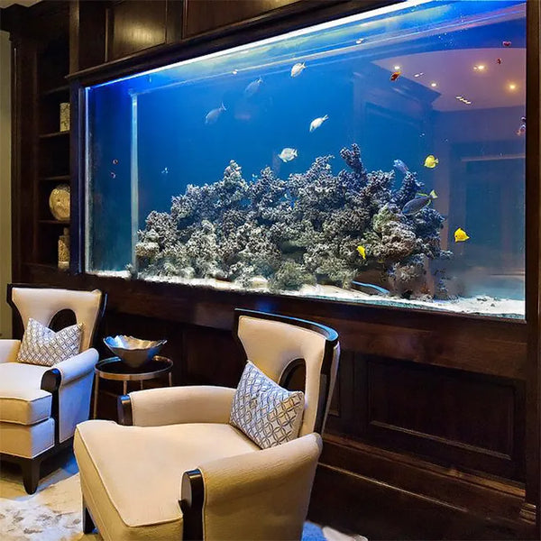 Reef aquarium inset into dark wood paneling beside chairs.
